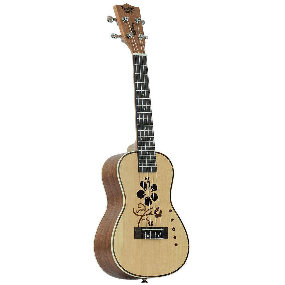 Three-quarter perspective view of Twelfth Note Crafted Series ukulele highlighting the engraved hibiscus soundhole design and side body contour